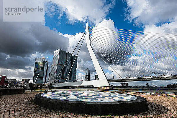 Impressive Erasmus bridge in Rotterdam harbor with dramatic sky and art in the foreground  Rotterdam  The Netherlands  Europe