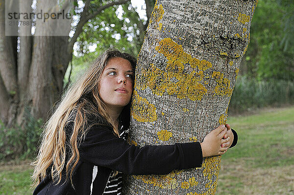 Young girl embracing the trunk of an ash tree  France  Europe