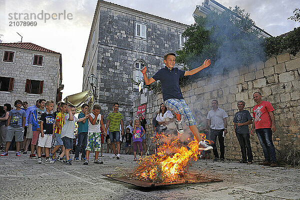 Young boys jumping over a wood fire beside the Cathedral St. Marka  Korcula old town  Korcula island  Croatia  Southeast Europe