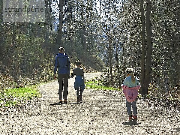 Mutter mit Sohn und Tochter beim Wandern und Spaß haben und zusammen glücklich sein und die Hände halten. Familienausflug in einem Wald im Frühling