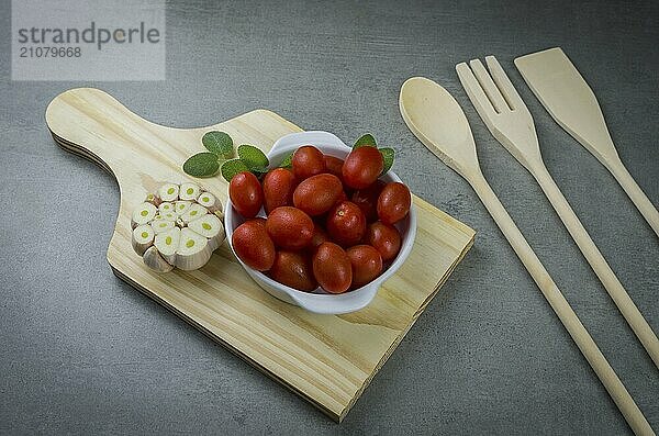 Holzbrett mit Kirschtomaten auf grauem Hintergrund. kulinarischen Hintergrund