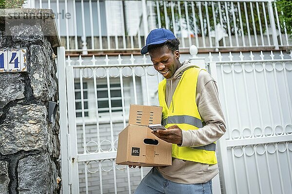 Liefernder afrikanischer junger Mann verwendet GPS  um die Adresse eines Kunden zu ermitteln