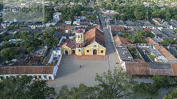 Luftaufnahme der wunderschönen historischen Kirche Santa Barbara (Iglesia de Santa Barbara) Santa Cruz de Mompox im Sonnenlicht mit Fluss und grüner Umgebung  Weltkulturerbe