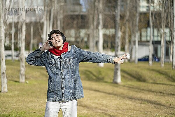 Young man listening to music outdoors with headphones. Expression of happiness