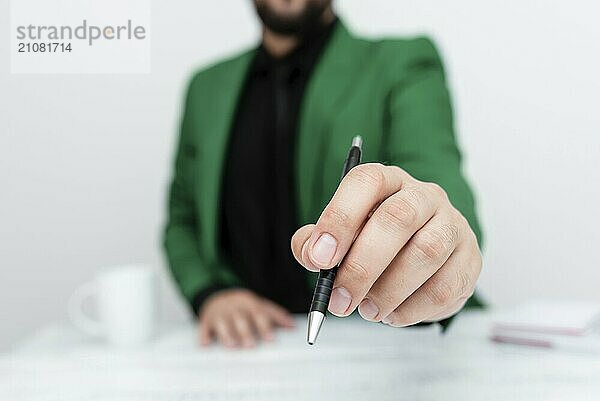 Männliche Person sitzt am Tisch und zeigt mit einem Stift auf eine wichtige Nachricht