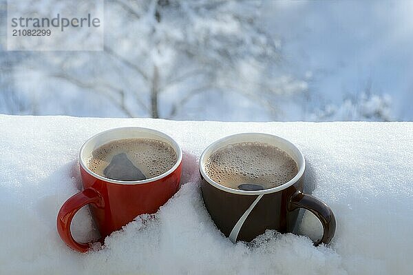 Dampfender heißer Kaffee in zwei Tassen  verschneit  auf dem Balkon  an einem hellen Wintermorgen. Frühstück für zwei. Gemütliches Winterkonzept