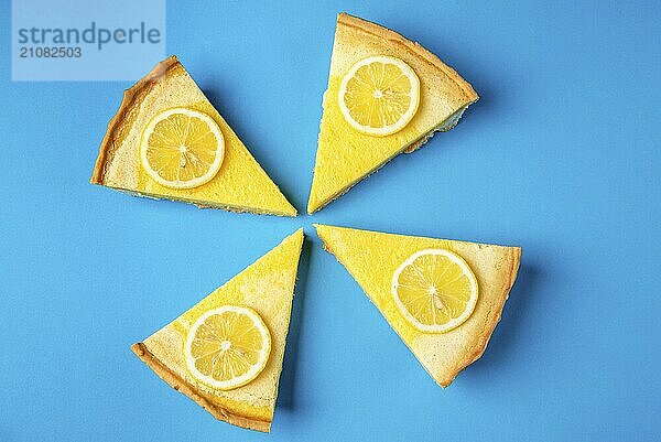 Vier Stücke Zitronenkuchen auf blauem Hintergrund  verziert mit gelben Zitronenscheiben. Hausgemachtes Gebäck. Süß saure Nachspeise. Zitruskuchen