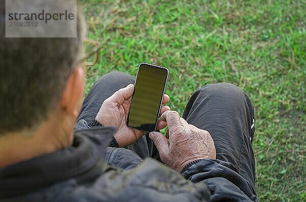 Nahaufnahme des faltigen Fingers eines Mannes  der ein Mobiltelefon berührt