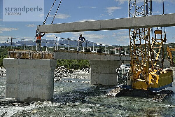 Builders construct a concrete bridge over a small river in Westland  New Zealand  Oceania