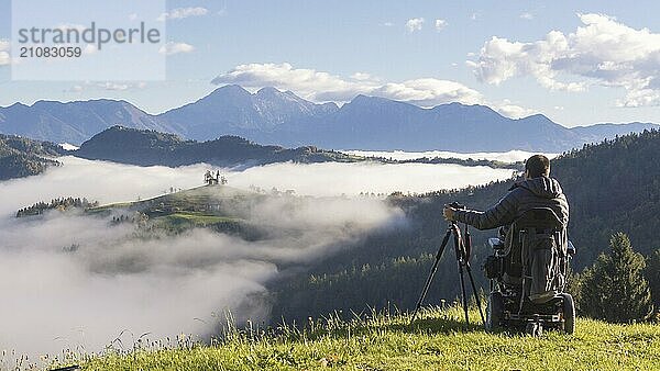 Mann im Rollstuhl macht Fotos von schöner Landschaft