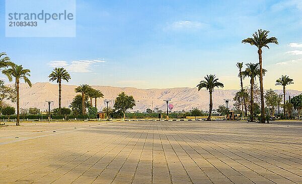 Platz in der Nähe des Karnak Tempels in Luxor mit Blick auf Palmen und Berge bei Sonnenaufgang