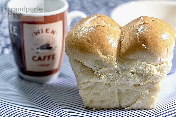 Mini Butter Brioche mit Kaffeebecher auf hellblauem Hintergrund