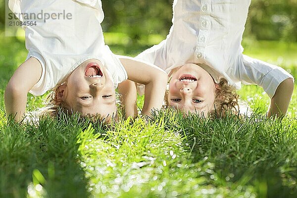 Glückliche Kinder spielen Hals über Kopf auf grünem Gras im Frühlingspark