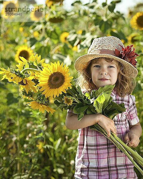 Glückliches lächelndes Kind mit einem Strauß Sonnenblumen im Frühjahrsfeld