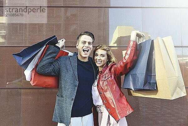 Beautiful young loving couple carrying shopping bags and enjoying together. Picture showing young couple shopping in the city