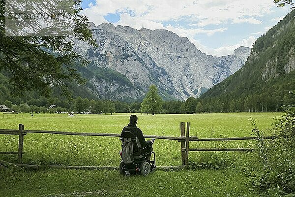 Happy man on wheelchair in nature. Exploring forest wilderness on an accessible dirt path