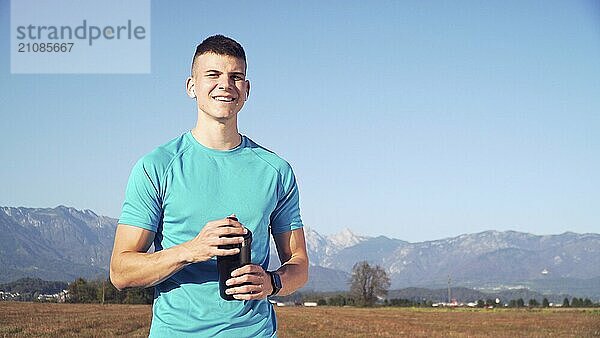 Fit junger Mann bereitet Protein Shake nach dem Training und trinken es mit Bergen den Rücken