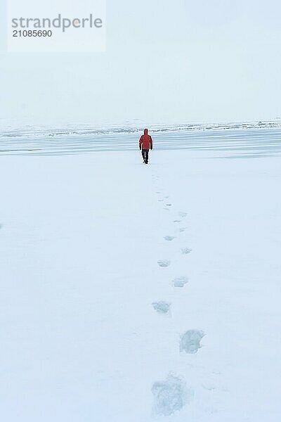 Fußabdrücke eines Mannes  der im kalten isländischen Winter über eine zugefrorene Lagune läuft