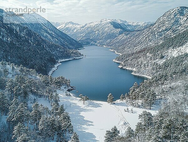 Luftaufnahme einer schneebedeckten Landschaft mit einem See  Bergen  Bäumen und einem bedeckten Himmel  AI generiert  KI generiert