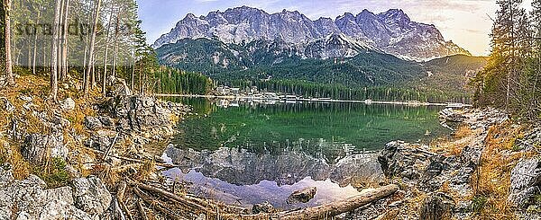 Alpenpanorama mit den Bergen der deutschen Alpen  die sich im Eibsee und im grünen Nadelwald spiegeln  bei Sonnenuntergang im Dezember