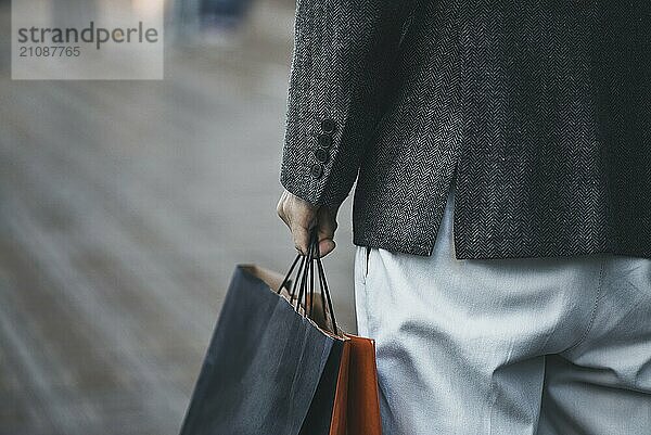 Nahaufnahme eines jungen kaukasischen Mannes  der auf der Straße verschiedene Einkaufstüten aus Papier hält