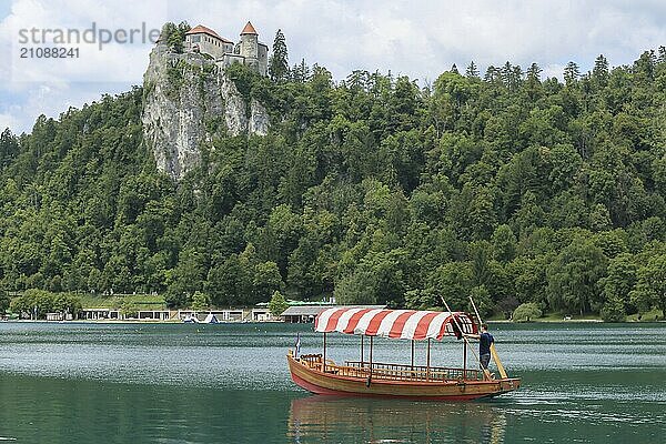 Bleder See mit traditionellem Boot. Schöner Bergsee im Sommer mit kleiner Kirche auf einer Insel mit Schloss auf einer Klippe und Alpen im Hintergrund