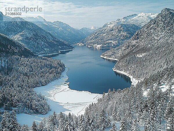 Ausgedehnte Winterlandschaft mit blauem See  umgeben von verschneiten Bergen und Wald aus der Luft  AI generiert  KI generiert