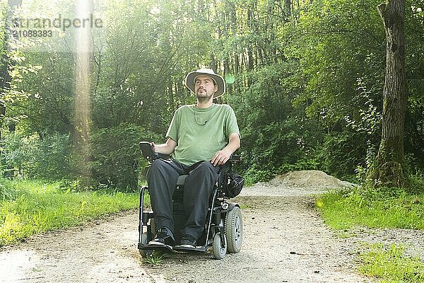 Lachender junger behinderter Mann im Rollstuhl