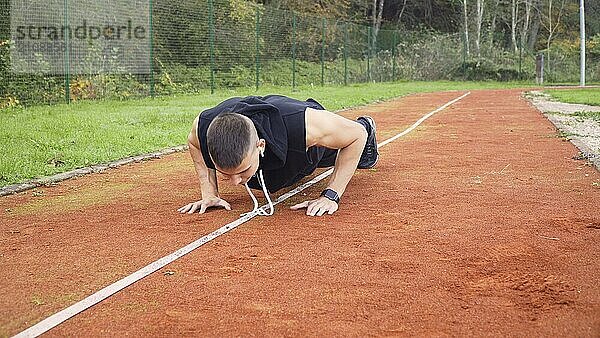 Junger fitter Mann macht morgens Liegestütze im Freien auf der Laufbahn. gesundes und aktives Konzept