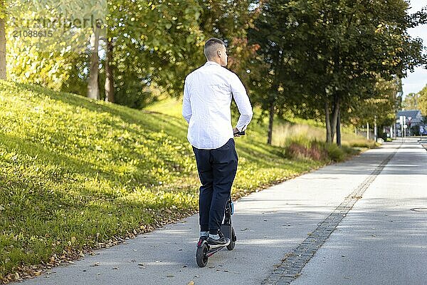 Fröhlicher und lässiger Mann fährt Elektroroller im Stadtpark