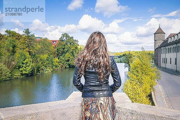 Junge Frau  mit dem Rücken zur Kamera  auf dem Rand einer Brücke  schaut zum Horizont  meditierend  in Schwäbisch Hall  Deutschland  Europa