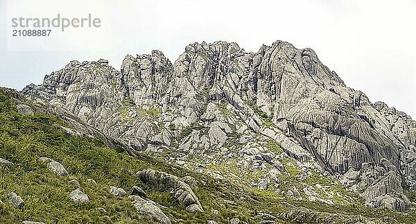 Landschaftlich zerklüftete Granitberge der Serra da Mantiqueira (Mantiqueira Gebirgskette) mit grasbewachsenen Teilen vor hellem Hintergrund  oberes Itatiaia  Brasilien  Südamerika