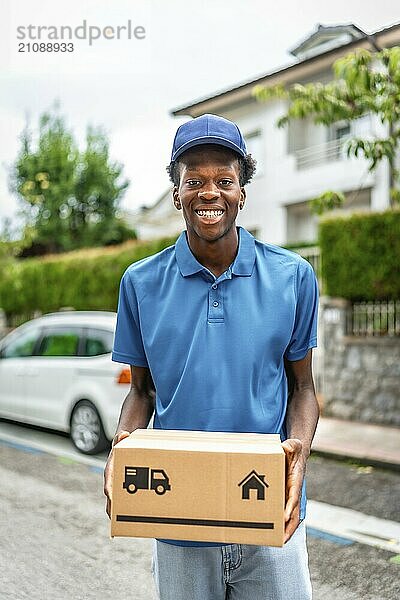 Vertikales Porträt eines fröhlichen afrikanischen Mannes mit einem Paket in den Händen