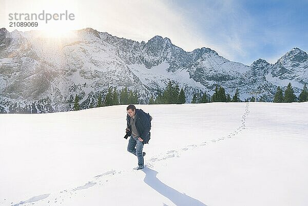 Repräsentatives Bild der Wintersaison  mit verschneiten Berggipfeln  Tannenwald und einem Mann  der durch eine dicke Schneeschicht wandert  in Ehrwald  Österreich  Europa