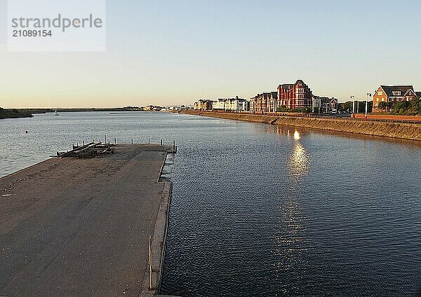 Ein Blick über den See in Southport bei Sonnenuntergang mit einem Steg vor den Gebäuden am Wasser