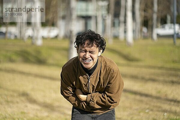 Young latin man falling about laughing