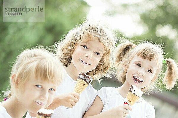 Glücklich lächelnde Kinder essen Eis im Freien im Frühling Park