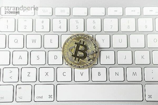 Foto von Cyptocurrency goldenen Bitcoin Festlegung auf weißen Tastatur im Hintergrund. Symbol der elektronischen virtuellen Geld