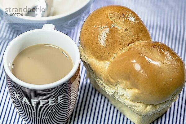 Mini Butter Brioche mit Kaffeebecher auf hellblauem Hintergrund