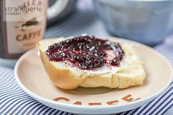 Mini Butter Brioche mit Marmelade und Kaffeebecher auf hellblauem Hintergrund