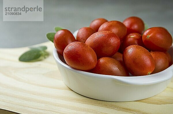 Holzbrett mit Kirschtomaten auf grauem Hintergrund. kulinarischen Hintergrund