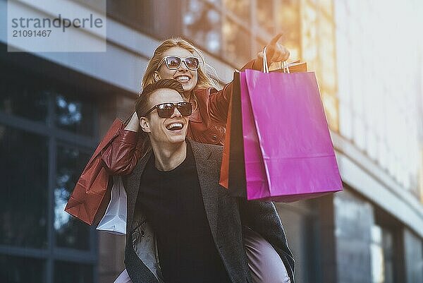 Happy couple shopping together and having fun. Boyfriend carrying his girlfriend on the piggyback