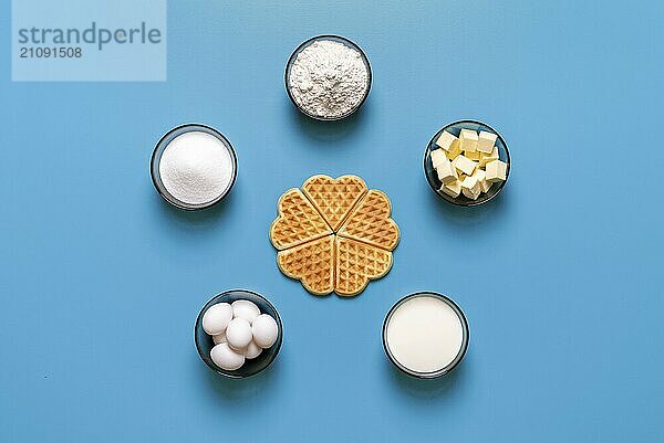 Ansicht von oben mit den Zutaten zum Backen belgischer Waffeln  minimalistisch auf blauem Hintergrund