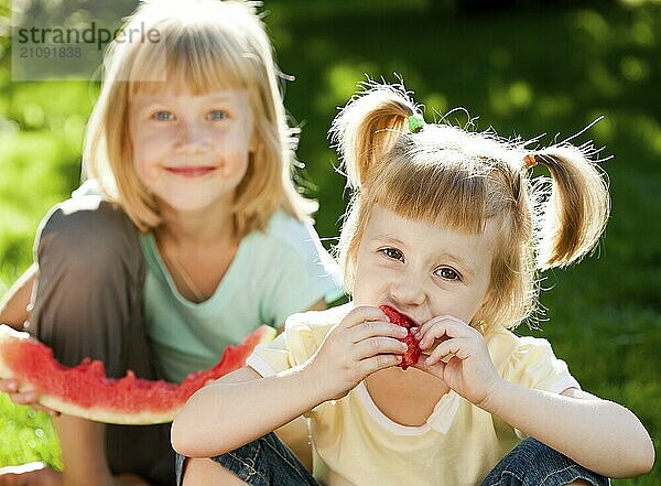 Fröhliche Kinder essen Wassermelone im Freien im Frühling Park