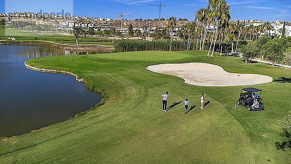 Aerial Drohne breite Ansicht von drei Menschen spielen in einem Luxus Golfplatz im Sommer