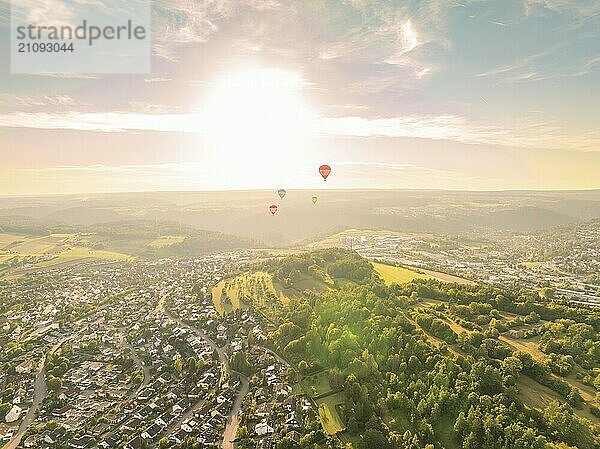 Heißluftballons fliegen über eine Stadt und bewaldete Hügel bei Sonnenuntergang  Calw  Schwarzwald  Deutschland  Europa