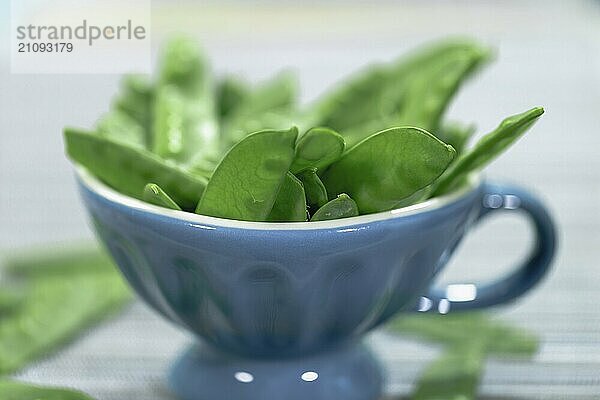 Zuckerschoten mit grauem Hintergrund und blauer Tasse