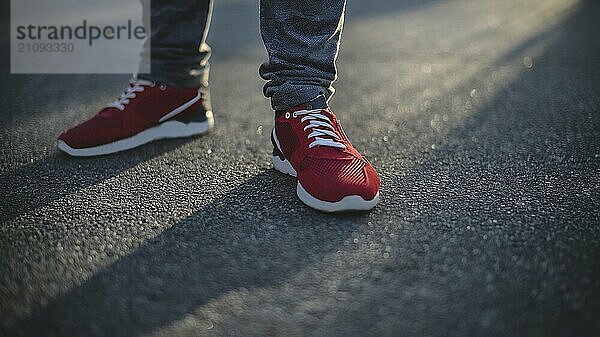 Mann in Turnschuhen geht an einem sonnigen Tag die Straße entlang