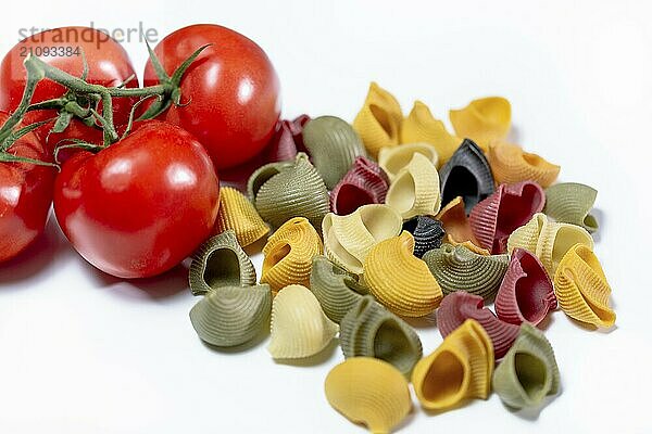 Farbige italienische Schneckenpasta aus Hartweizengrieß mit roten Strauchtomaten vor weißem Hintergrund