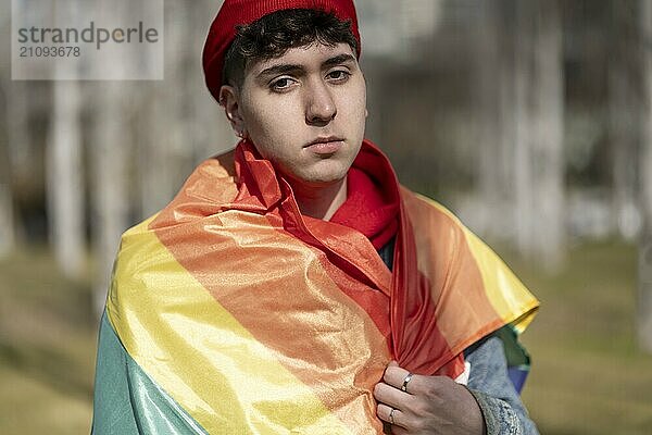 Junge Homosexuell Mann in lgbt Flagge gewickelt Blick ernst in die Kamera